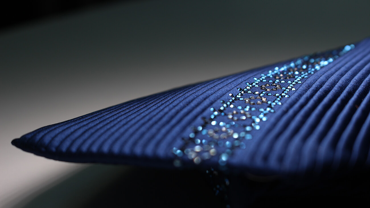 プリーツ加工を施したネイビーのネクタイにクリスタルガラスが施された美しい商品の写真